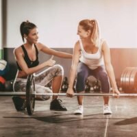 L'immagine raffigura un personal trainer con la sua cliente in fase di allenamento