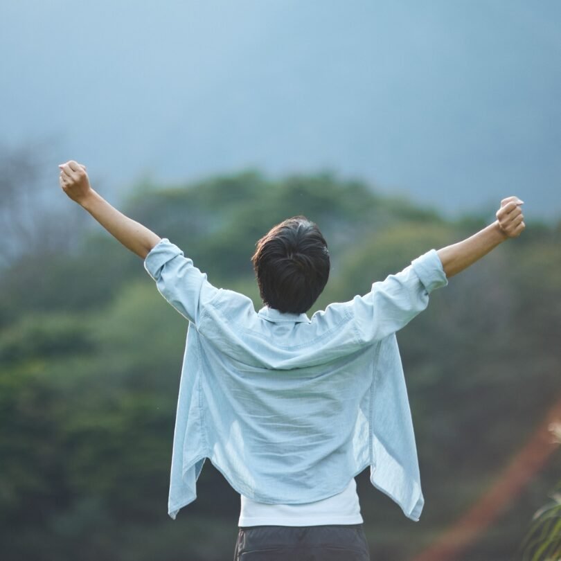 Persona con le braccia alzate verso il cielo, immersa nella natura: simbolo di liberazione, rinascita interiore e inizio di un nuovo percorso personale