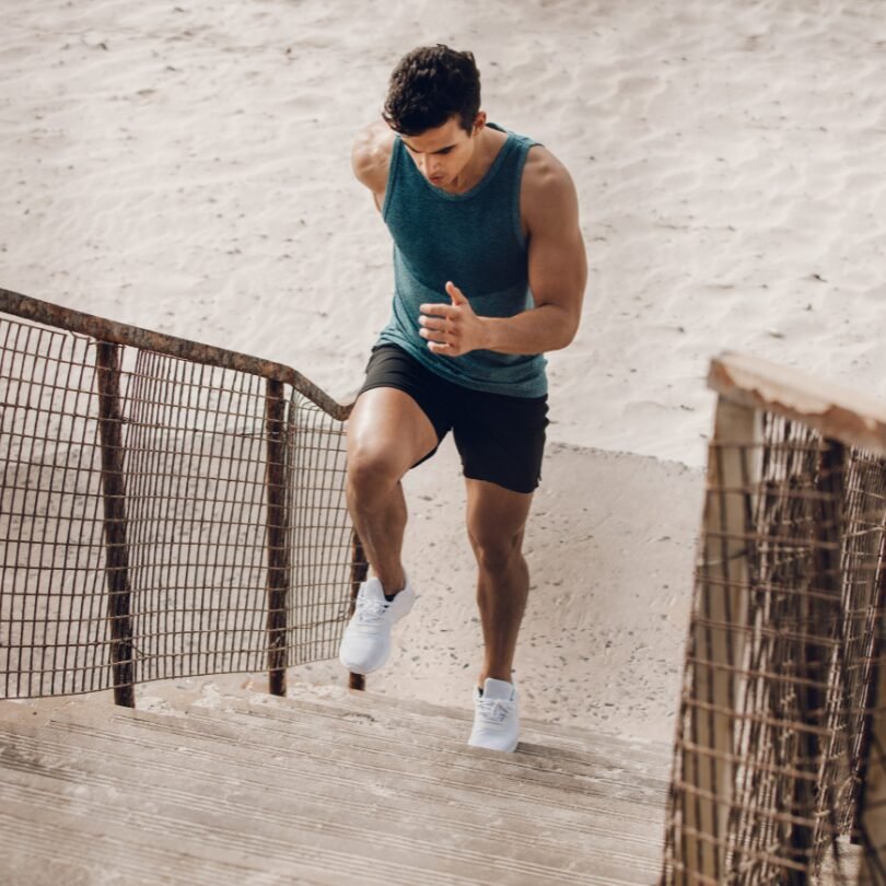 Uomo che corre energicamente su una scalinata in spiaggia, simbolo di determinazione e benessere. Rappresenta come l’attività fisica sia uno strumento concreto per combattere ansia e stress, migliorare la concentrazione e ritrovare equilibrio mentale