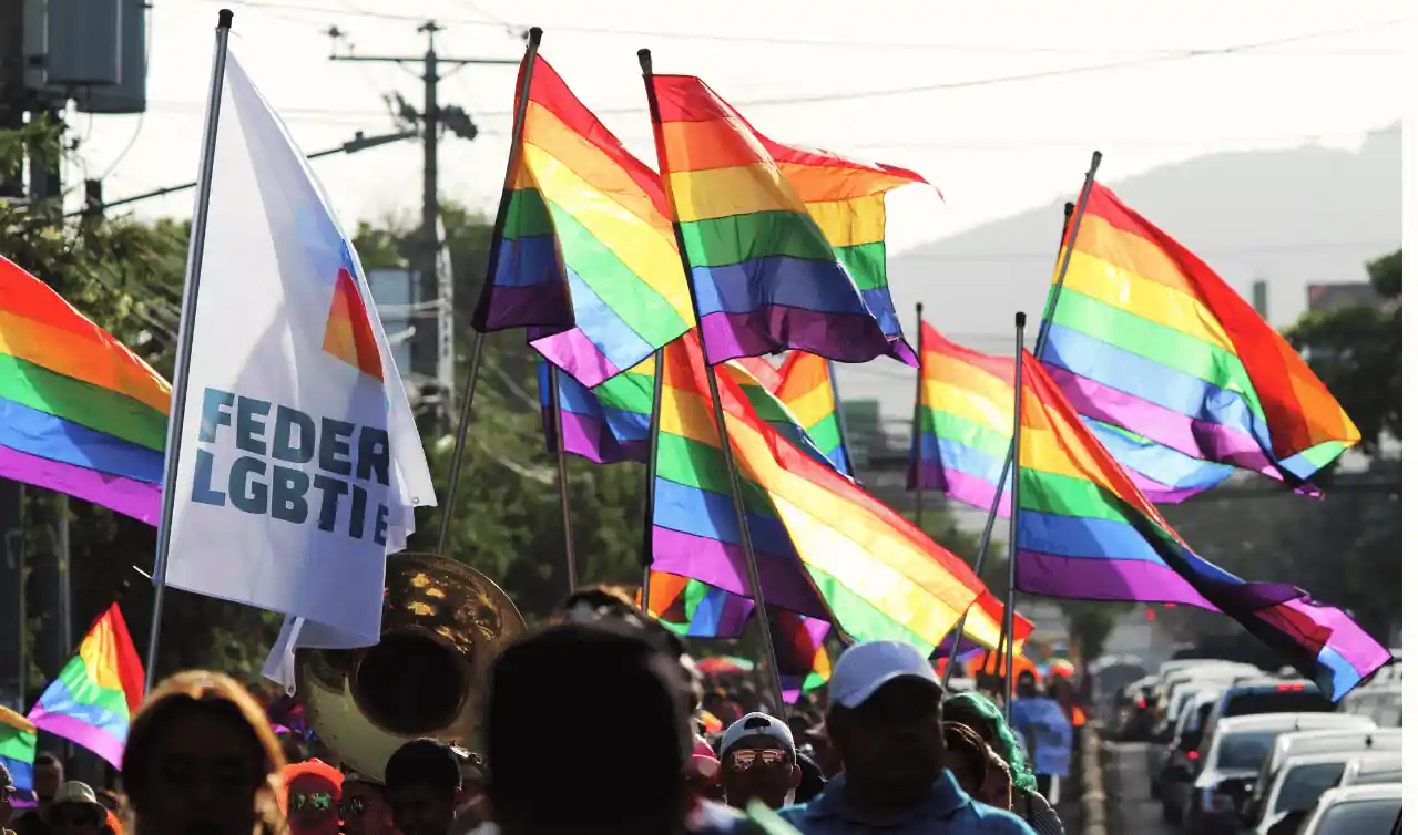 Manifestazione con bandiere arcobaleno, simbolo di dignità, inclusione e libertà nel lavoro